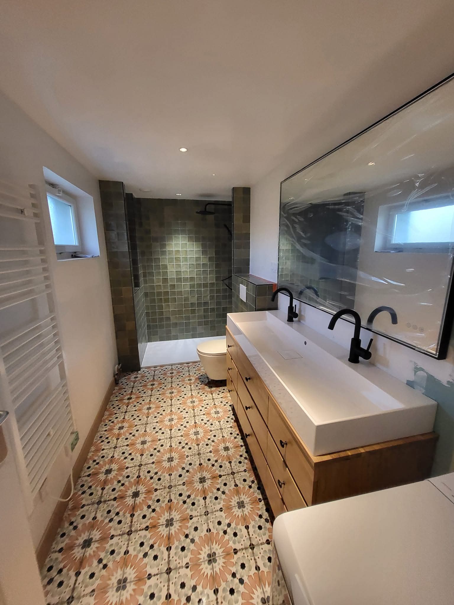 Salle de bain restaurée par Artena : douche en zellige vert émeraude et sol en carreaux de ciment